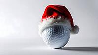A golf ball wearing a bright red Santa hat, casting a shadow on a white background, creatively blends holiday cheer with the sport. This festive decoration adds a playful touch to golf during the winter season. AI generated [IBR123641859]