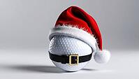 A golf ball wears a bright red Christmas hat with white trim and a black belt. This festive decoration brings a playful touch to the holiday season, blending sports and celebration. AI generated [IBR123641860]