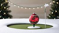 A red decorative ornament sits on a snowy putting green near a small flag. Strings of lights twinkle softly in the background, creating a festive atmosphere during winter holidays. AI generated [IBR123641861]