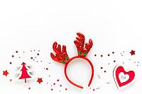Christmas art composition with red decorations, reindeer headband on white surface. Christmas celebration concept. Flat lay, top view, copy space, greeting card [IBR123646491]
