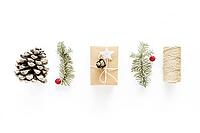 Christmas gift art composition on white surface. Gifts, christmas wooden decorations, fir branches, pine cone. Handmade DIY concept. Flat lay, top view. Winter flatlay holiday background [IBR123646493]