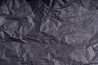 Dark wrinkled creased black paper poster texture. Blank crumpled grainy paper textured surface. Smudged grungy cardboard with fiber. Close up. Material tissue for packing [IBR123646513]