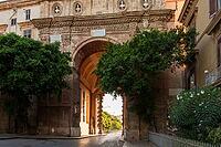 Close-up view of the archway of Porta Nuova in Palermo, Sicily, highlighting detailed stonework and decorative elements, framed by trees and illuminated by sunlight [IBR123646557]