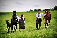 Young couple on national dress with horses [IBR123675139]