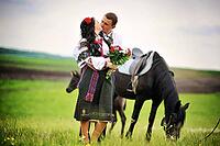 Young couple on national dress with horses [IBR123675142]
