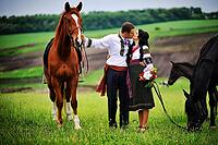 Young couple on national dress with horses [IBR123675145]