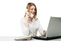 Young professional business woman working at her desk with laptop and smiling while calling and having telephone conversation over white background [IBR123723198]