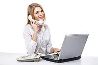 Young professional business woman working at her desk with laptop and smiling while calling and having telephone conversation over white background [IBR123723199]