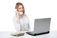 Young professional business woman working at her desk with laptop and smiling while calling and having telephone conversation over white background [IBR123723200]
