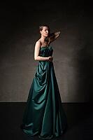 Model in beautiful long dress with arm raised looking down.Studio shot [IBR123723218]