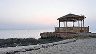 A pavilion on a rocky beach surrounded by the sea at sunset in a calm and peaceful atmosphere, Shoni Bay, Egypt [IBR123769626]