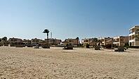 Beach with sand and palm trees in front of modern houses under clear skies, Shoni Bay, Egypt [IBR123769640]