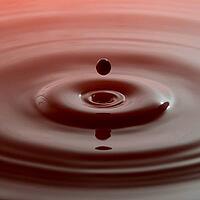 Red paint droplet over rippled paint surface [IBR123878836]