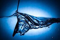 Spoon making waves in fresh water with blue background [IBR123878844]