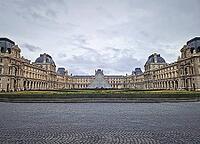 Paris, France - December 10, 2025: The ornate Renaissance facade and the iconic glass Pyramid of the Louvre Museum with multiple tourists scattered across the vast cobblestone courtyard [IBR123895589]