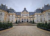 Maincy, France - December 11, 2025: Grand facade of Chateau de Vaux-le-Vicomte with cobblestone courtyard. Beautiful Baroque architecture decorated with small evergreen trees for the winter holidays [IBR123895601]