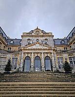 Maincy, France - December 11, 2025: Grand facade of Chateau de Vaux-le-Vicomte with cobblestone courtyard. Beautiful Baroque architecture decorated with small evergreen trees for the winter holidays [IBR123895603]