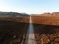 Aerial view, infinite space, straight road leads through dry desert landscape, hills in Damaraland, Namibia [IBR123990966]
