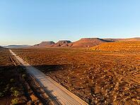 Aerial view, road leading through dry desert landscape, hills in Damaraland, Namibia [IBR123990970]