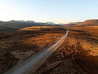 Aerial view, road leading through dry desert landscape, hills in Damaraland, Namibia [IBR123990975]