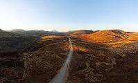 Aerial view, road leading through dry desert landscape, hills in Damaraland, Namibia [IBR123990978]