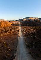 Aerial view, infinite space, straight road leads through dry desert landscape, hills in Damaraland, Namibia [IBR123990980]