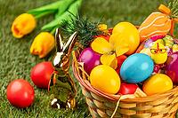 A basket with colorful eggs, flowers and Easter decoration in a meadow [IBR123990986]