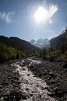 Sunny alpine valley with rocky stream leading to snow-capped peaks Oeschinensee area, Kandersteg, Canton of Bern, Switzerland [IBR123990988]