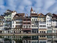 Colourful historic tuna facades on the banks of the river are reflected in the Aare — medieval tower, balconies and Swiss lakeside charm [IBR123990989]