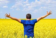 Free man in the field. The man raised his hands up. Field of flowering rape [IBR123999802]