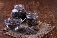 Chia seeds in small jars on wooden background, selective focus [IBR123999881]