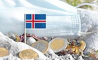 Icelandic flag with euro currency coins and a medical mask on rocky ground.International healthcare costs, cross-border medical funding, Europe and Iceland cooperation and global health finance [IBR124084099]