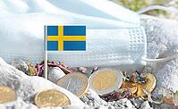Swedish flag with euro currency coins and a medical mask on rocky ground.International healthcare costs, medical funding, Europe and Sweden cooperation and global health finance [IBR124084107]