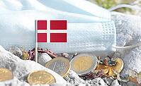 Danish flag with euro currency coins and a medical mask on rocky ground.International healthcare costs, cross-border medical funding, Europe–Denmark cooperation and global health finance [IBR124084115]