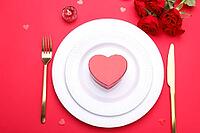 Romantic table setting, gold cutlery on the red table cloth. Valentine's day celebration [IBR124084185]