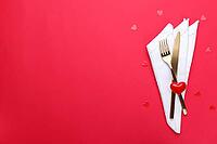 Romantic table setting, gold cutlery on the red table cloth. Valentine's day celebration [IBR124084186]