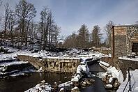 The ruins of the historic Borgvik Ironworks. Industrial stone architecture on a river in winter with snow and blue skies. Cultural heritage site in picturesque countryside in Värmland, Sweden [IBR124200520]