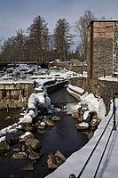 The ruins of the historic Borgvik Ironworks. Industrial stone architecture on a river in winter with snow and blue skies. Cultural heritage site in picturesque countryside in Värmland, Sweden [IBR124200521]
