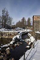The ruins of the historic Borgvik Ironworks. Industrial stone architecture on a river in winter with snow and blue skies. Cultural heritage site in picturesque countryside in Värmland, Sweden [IBR124200523]
