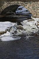 The ruins of the historic Borgvik Ironworks. Industrial stone architecture on a river in winter with snow and blue skies. Cultural heritage site in picturesque countryside in Värmland, Sweden [IBR124200524]
