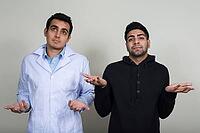 Studio shot of two young Indian men as doctor and patient together against white background [IBR124308998]