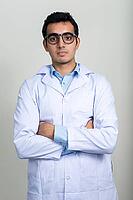 Studio shot of young handsome Indian man doctor against white background [IBR124309009]