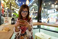 Portrait of young beautiful Asian woman relaxing at the coffee shop [IBR124309015]