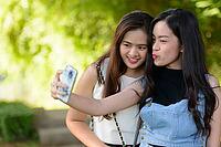Portrait of two young Asian women as friends together relaxing at the park outdoors [IBR124309017]