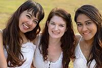 Portrait of three multi ethnic young beautiful women as friends together at the park outdoors [IBR124309044]