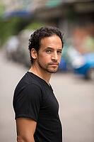 Portrait of handsome bearded Hispanic man with curly hair in the streets outdoors [IBR124309057]