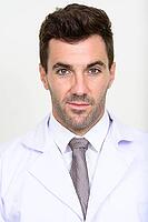 Studio shot of handsome Hispanic man doctor against white background [IBR124309061]