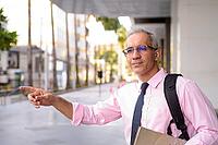 Portrait of handsome Persian businessman with gray hair outside modern building in the city [IBR124309082]