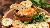 Creamy orange dip in a wooden bowl surrounded by crispy bread chips, delicious dip, perfect as a side dish for meals and parties, AI generates, AI generated [IBR124458833]