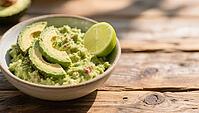 Bowl of guacamole decorated with avocado and lime slice on a wooden table surface, delicious dip, perfect as a side dish for meals and parties, AI generates, AI generated [IBR124458873]